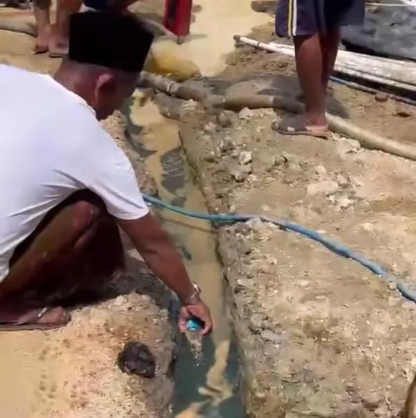 Warga mengamati cairan diduga minyak yang keluar dari lubang pengeboran sumur air bersih di Desa Panyaksagan, Kecamatan Klampis, Kabupaten Bangkalan, Jawa Timur, Kamis (8/1/2026). Lokasi pengeboran sementara diamankan BPBD Bangkalan guna mencegah potensi bahaya, sembari menunggu pemeriksaan lanjutan dari ESDM Provinsi Jawa Timur (foto/Syah)